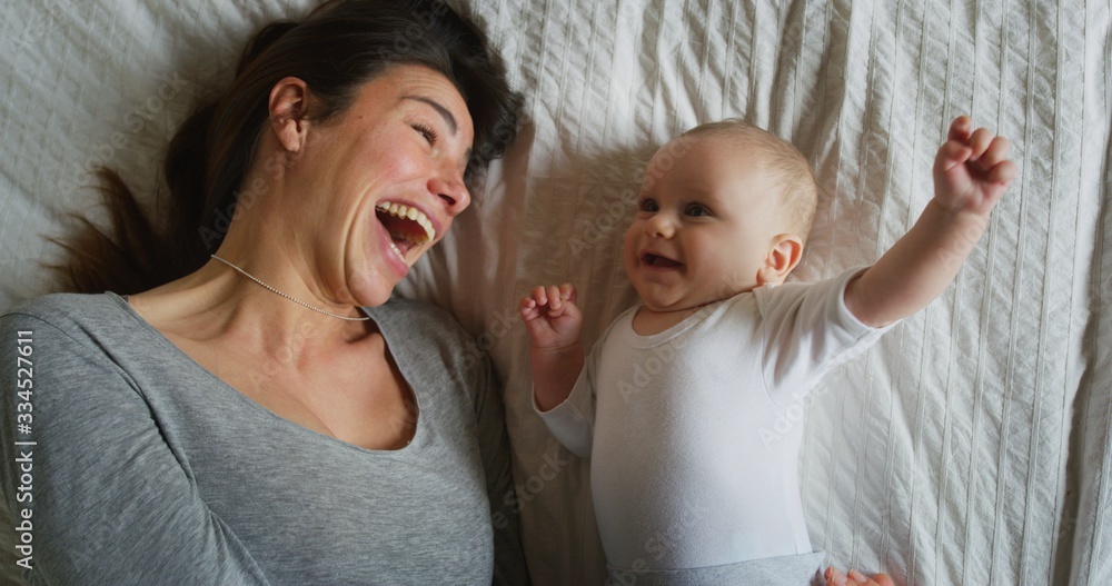 Authentic shot of young happy neo mother is having fun with her newborn baby in a nursery in a morning.Concept of children,baby, parenthood,childhood, life, maternity, motherhood, happiness, authentic