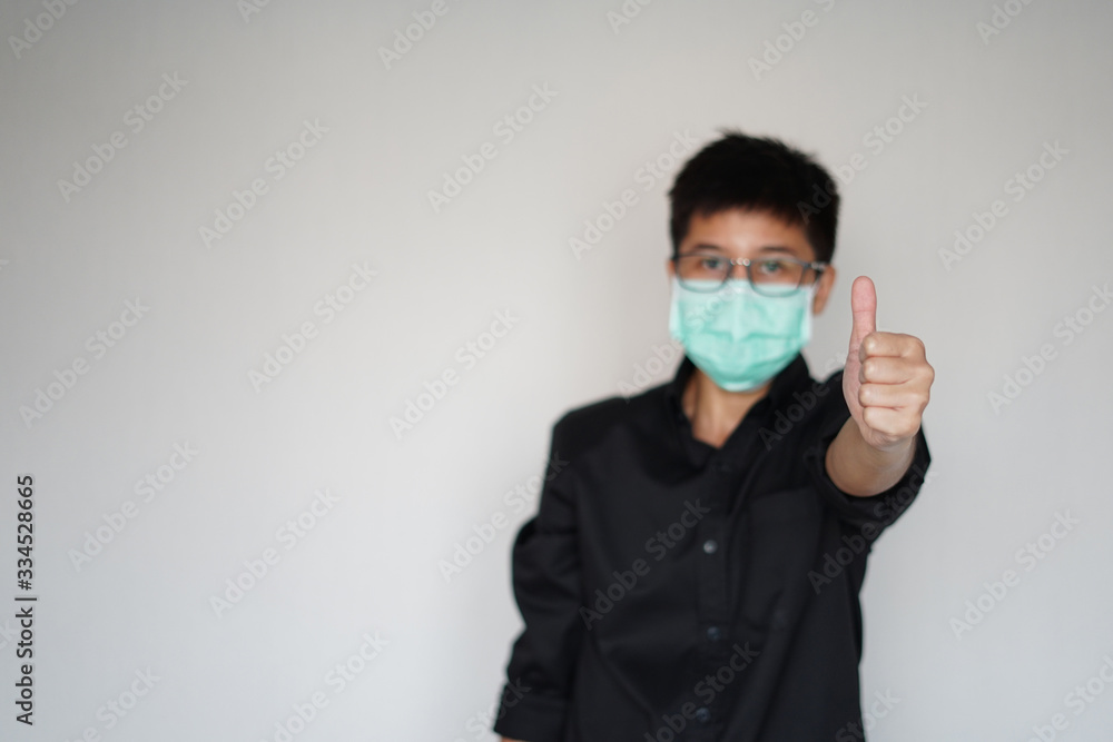 Young man wearing face hygienic mask for prevention global coronavirus pandemic outbreak. He lift hand great we will suvive. Young man wearing face hygienic mask for prevention global coronavirus pandemic outbreak. He lift hand great we will suvive.