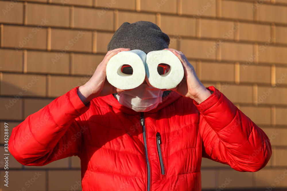 A man in a medical mask holds rolls of toilet paper A man in a medical mask holds rolls of toilet paper
