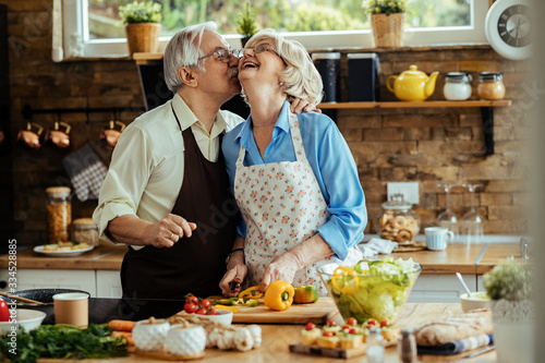Affectionate senior couple having fun while preparing food in the kitchen.