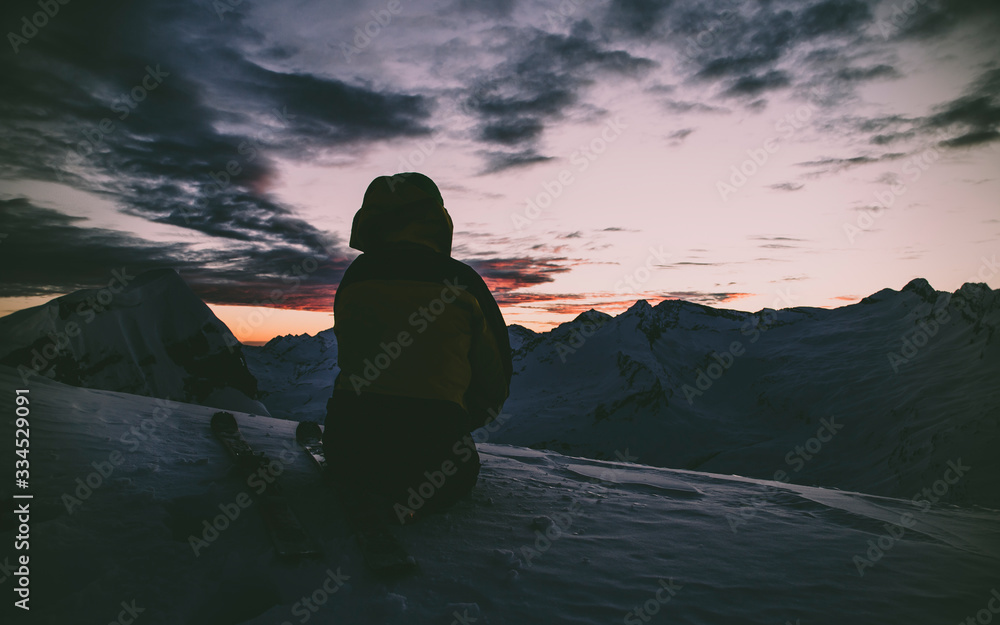 Men silhouette in the darkness of the winter. Sunset in the Swiss Alps.