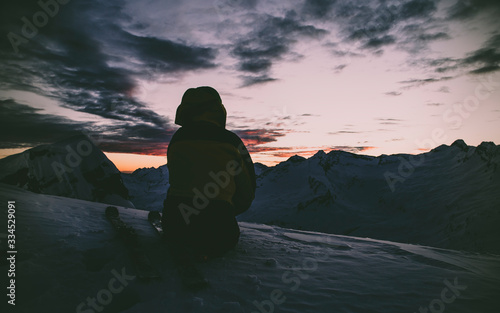 Men silhouette in the darkness of the winter. Sunset in the Swiss Alps.