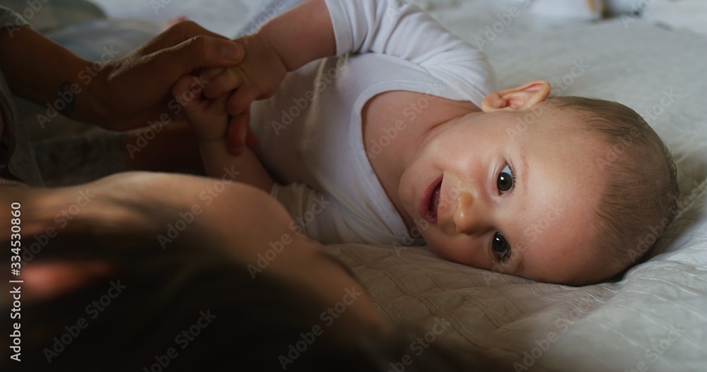 Authentic shot of young happy neo mother is playing with her newborn baby in a nursery in a morning.Concept of children,baby, parenthood,childhood, life, maternity, motherhood, happiness, authenticity Authentic shot of young happy neo mother is playing with her newborn baby in a nursery in a morning.Concept of children,baby, parenthood,childhood, life, maternity, motherhood, happiness, authenticity
