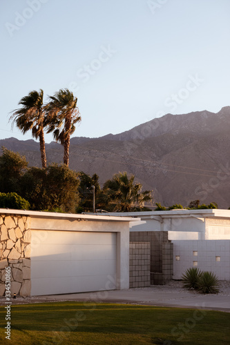 mid-century house below mountains and palms