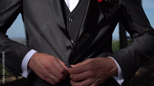The man fastens his tuxedo.Buttoning a jacket. Stylish man in a suit fastening buttons on his jacket
