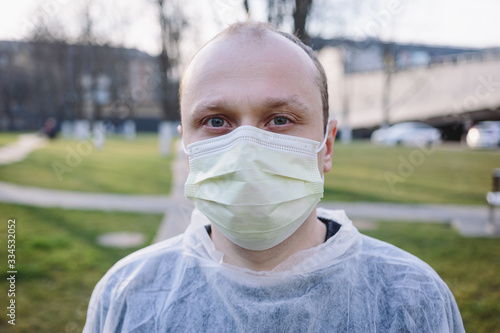 Closeup portrait of young man in yellow protective mask and medical gown on the street. Pandemic coronavirus 2020. Quarantine.Virus concept. Epidemic infection.