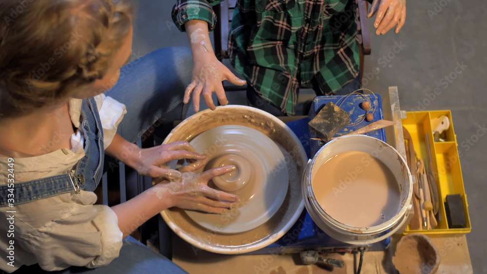 Fototapeta premium Slow motion, woman works with pottery wheel in a workshop