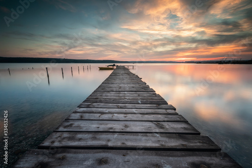 Magnificent long exposure lake sunset with boat and a wooden pier