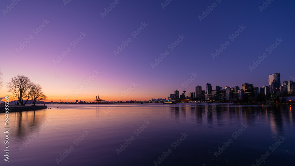 Sunrise over downtown Vancouver and Stanley park with water reflection