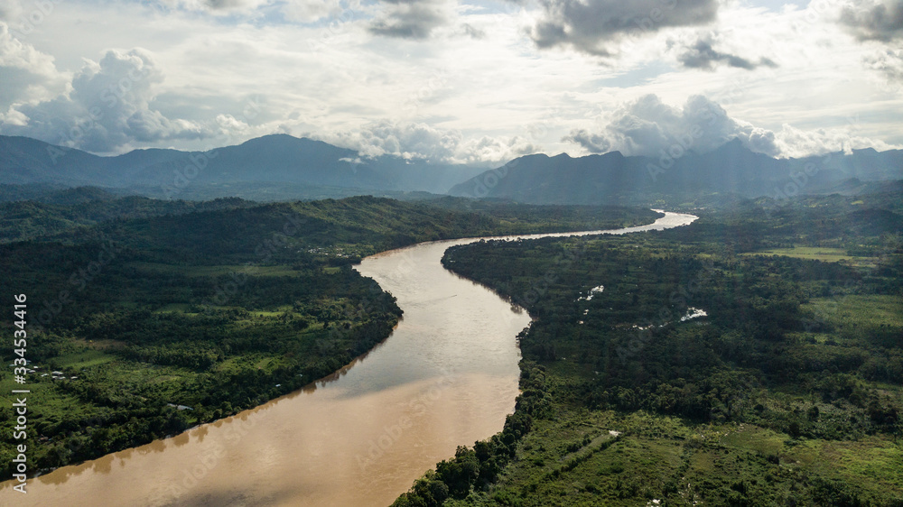 Aerial view of river in the amazon jungle in Peru with mountains Andes in the background. Green lungs, mother earth, valley. 