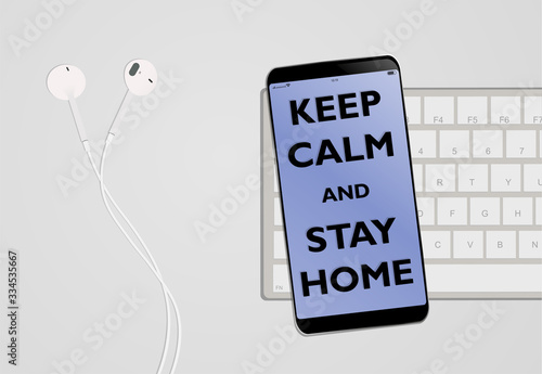Desk with headphones, smartphone and keyboard with text keep calm and stay home