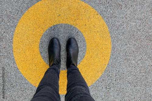 Black shoes standing in yellow circle on the asphalt concrete floor. Comfort zone or frame concept. Feet standing inside comfort zone circle photo