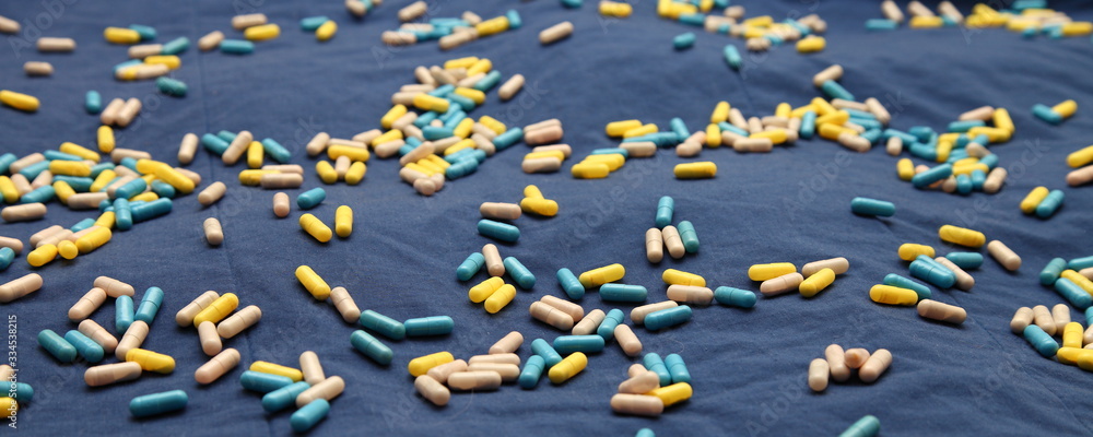 A many colored capsules in prespective on blue background, COVID-19 Coronavirus prophylactic picture for header A many colored capsules in prespective on blue background, COVID-19 Coronavirus prophylactic picture for header