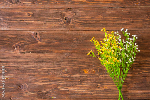 Colorful yellow, white and lilac spring flowers on rustic brown painted wooden planks. View from above. © Alik Mulikov
