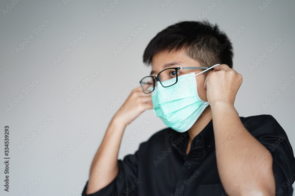 Close up the young man wearing face hygienic mask for prevention global covid-19 virus pandemic. The corona-virus from Wuhan is dangerous. People need quarantine. Close up the young man wearing face hygienic mask for prevention global covid-19 virus pandemic. The corona-virus from Wuhan is dangerous. People need quarantine.