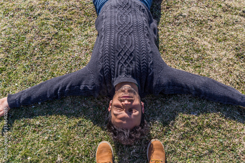 Φωτογραφία relaxed and happy dark-haired man lying on the grass with open arms