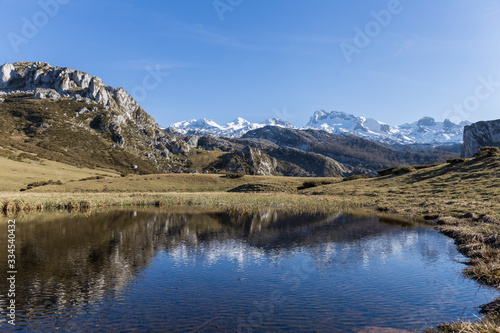 mountainous landscape, small lake in which the mountain, the meadow and the blue sky are reflected