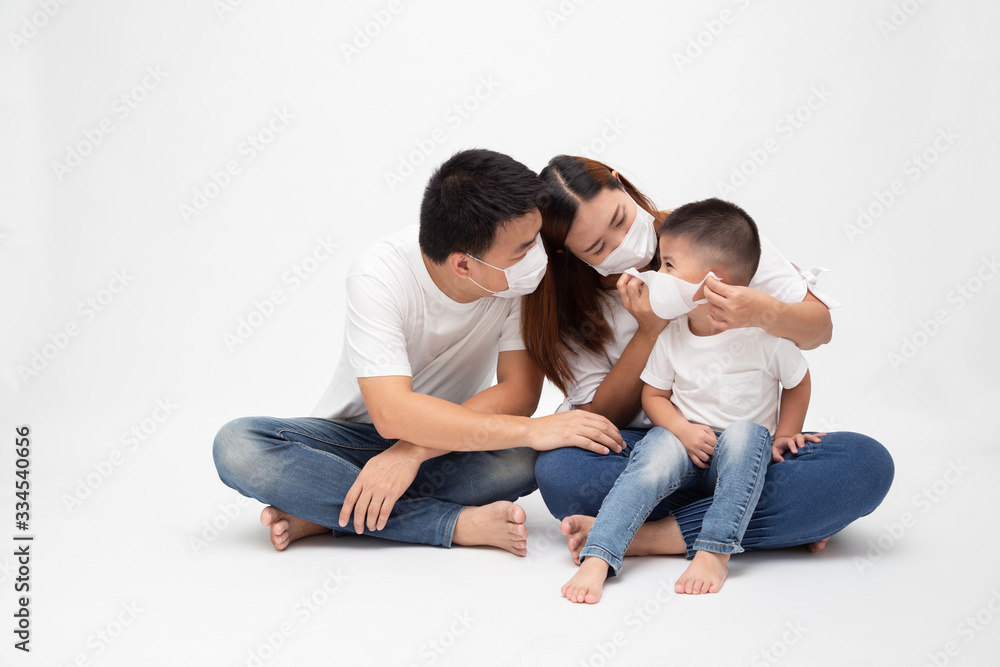 Asian family wearing protective medical mask for prevent virus Wuhan Covid-19 and sitting together on floor isolated white background. Family protection from contaminated air concept Asian family wearing protective medical mask for prevent virus Wuhan Covid-19 and sitting together on floor isolated white background. Family protection from contaminated air concept