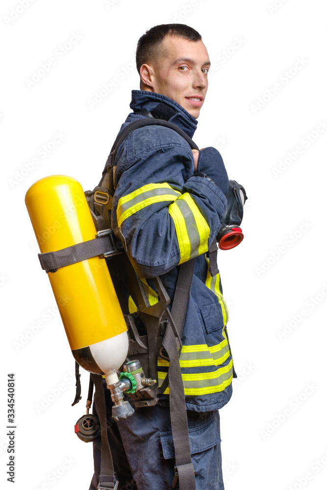 Young caucasian firefighter posing in profile with Full Facepiece Respirator and Breathing Air Cylinder Assembly on his back in fireproof uniform isolated on white background Young caucasian firefighter posing in profile with Full Facepiece Respirator and Breathing Air Cylinder Assembly on his back in fireproof uniform isolated on white background