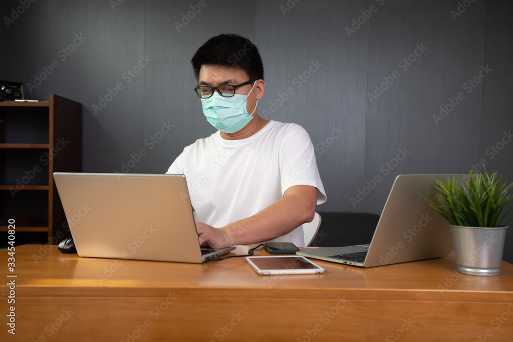 Asian man it support working with computer laptop to remote desktop and wearing protective medical mask for prevent virus Wuhan Covid-19. Work from home concept Asian man it support working with computer laptop to remote desktop and wearing protective medical mask for prevent virus Wuhan Covid-19. Work from home concept