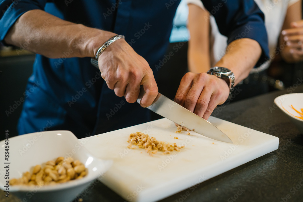 Chef chopping peanuts on a table to prepare some delicious asian noodles