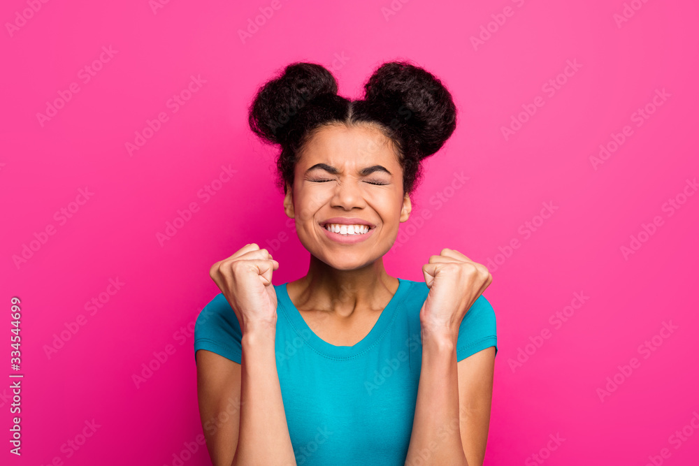 Closeup photo of crazy funky dark skin lady two buns hairdo good mood raise fists celebrating amazing success achievement wear blue casual t-shirt isolated vivid pink color background Closeup photo of crazy funky dark skin lady two buns hairdo good mood raise fists celebrating amazing success achievement wear blue casual t-shirt isolated vivid pink color background
