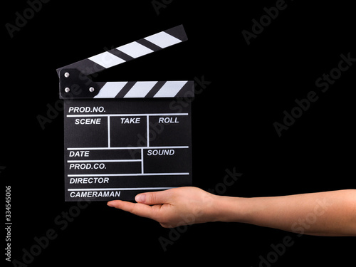 Human hand holding film clapper board isolated on black background. photo