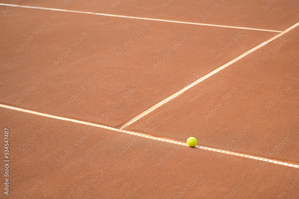 Abandoned tennis ball on a line on a clay tennis court. Lines on a clay tennis court. No match.
