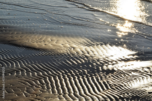 Shiny wet sand on the beach reflecting golden sunset
