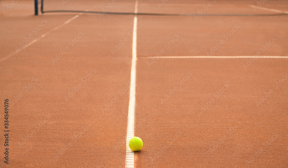 Tennis ball on a line on a lonely clay tennis court. No match.