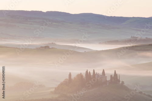 Beautiful colors of green spring panorama landscape of Tuscany. Most popular place in Italy. Green fields and blue sky and Cypress tree scenic road near Siena. Amazing foggy morning with sunshine photo