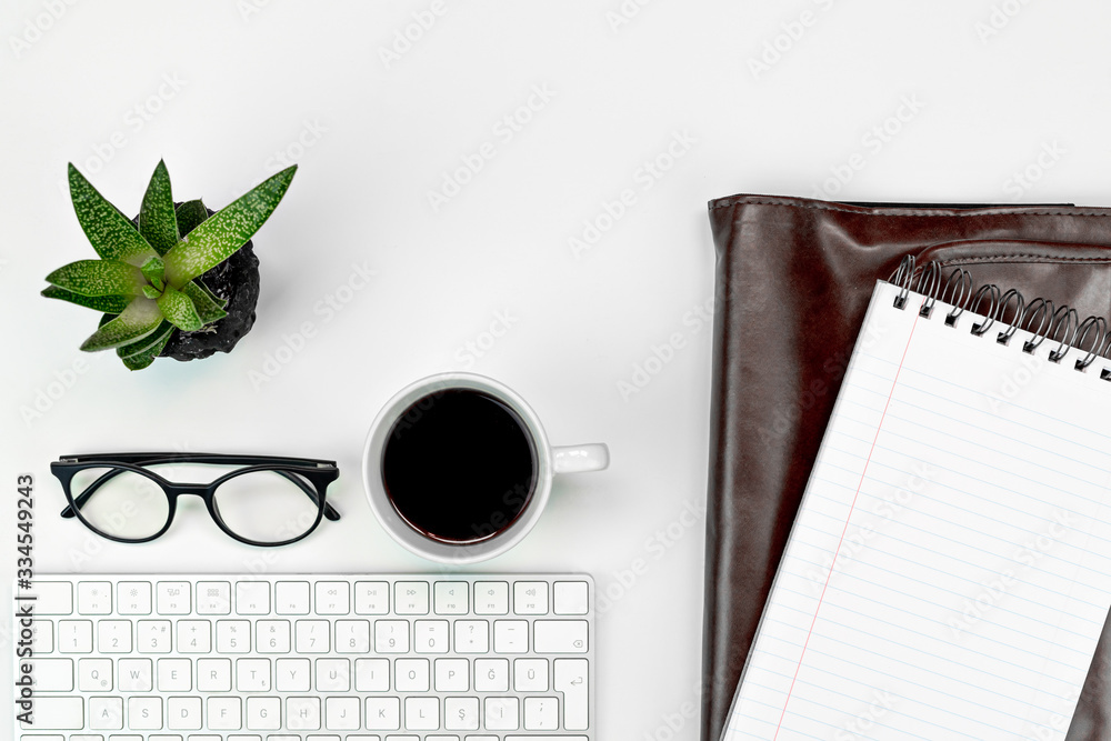 White office table, computer keyboard, glasses, cup of coffee and office supplies. Top view with copy space, flat lay White office table, computer keyboard, glasses, cup of coffee and office supplies. Top view with copy space, flat lay
