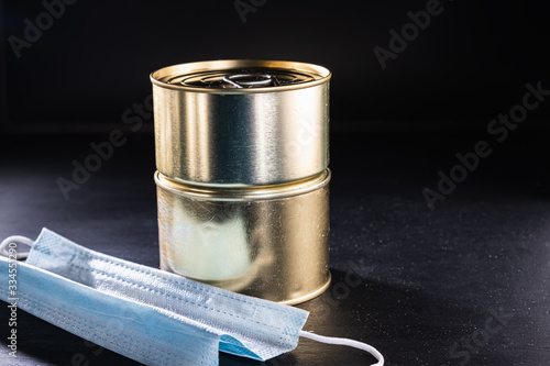 medical mask and two cans of canned food on a dark background. horizontal. central photo