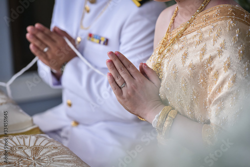 Bride and groom praying hand with holy thread blessing for happiness in their new family life.Thailand traditional wedding and engagement decoration accessories