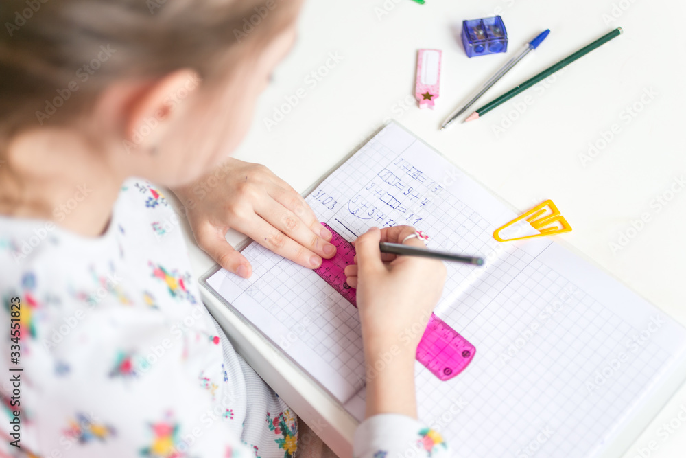 Close up of a girl writing math exercise at home. Selected focus.