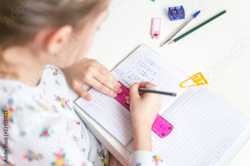 Obraz na płótnie Close up of a girl writing math exercise at home. Selected focus. w salonie