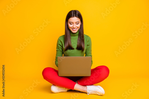 Photo of beautiful lady sitting floor holding notebook reading online lecture writing creative homework composition wear green sweater red trousers isolated yellow color background photo