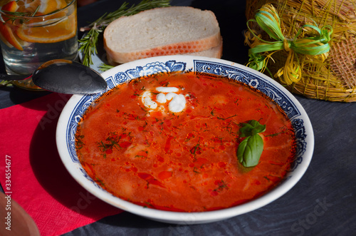 Traditional Russian and Ukrainian borsch, red soup with bread on a dark background. Borsch with meat, sour cream and dill. Overhead Copy Space