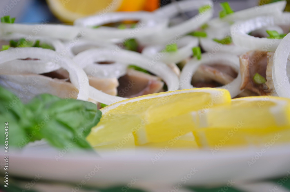 Herring fillet with salt, pepper, herbs, onion and lemon on black plate on white background. top view. healthy food Herring fillet with salt, pepper, herbs, onion and lemon on black plate on white background. top view. healthy food