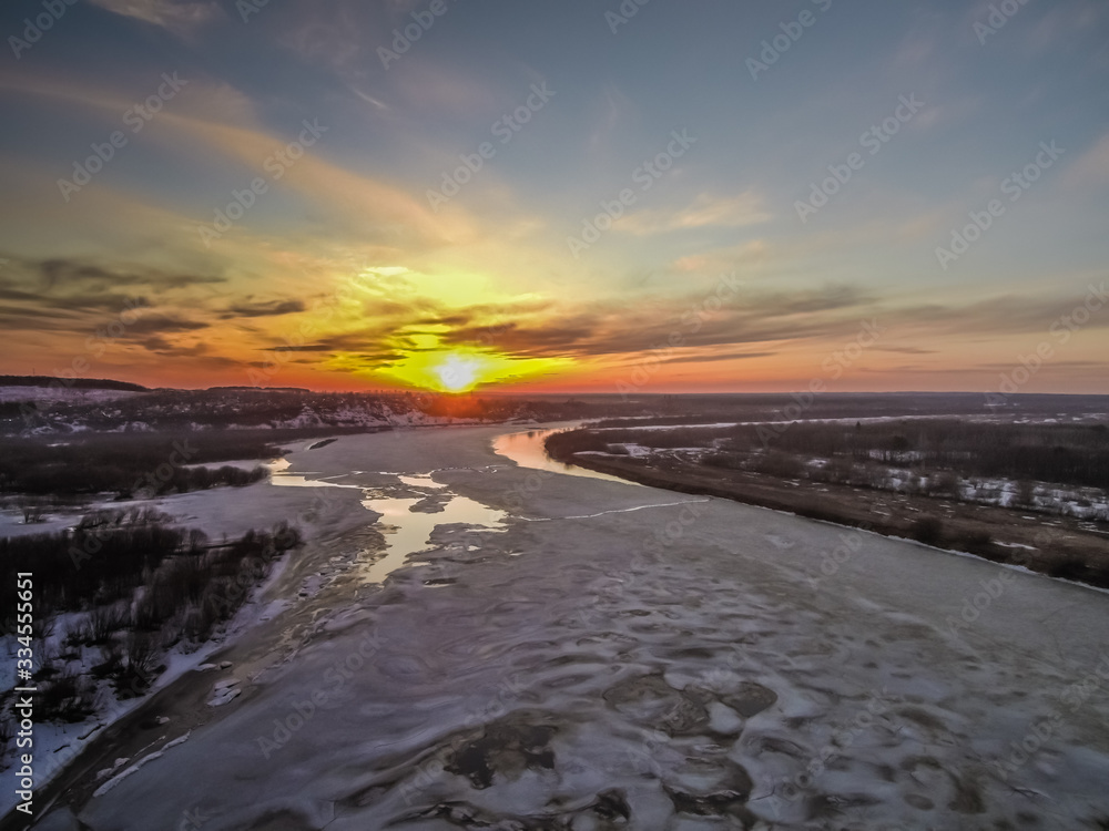 beautiful sunset over the spring river opened from ice