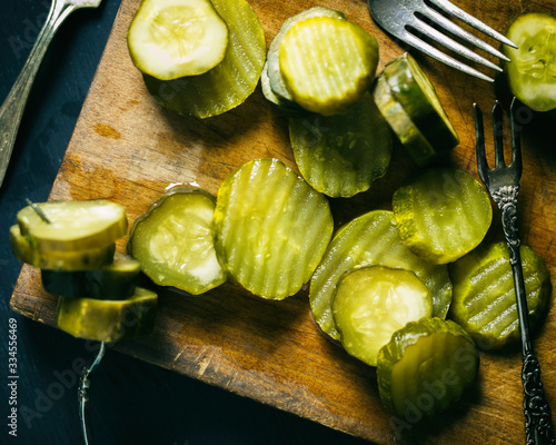 Sliced artisan pickles on a wooden cutting board. Homemade pickle chips.  photo