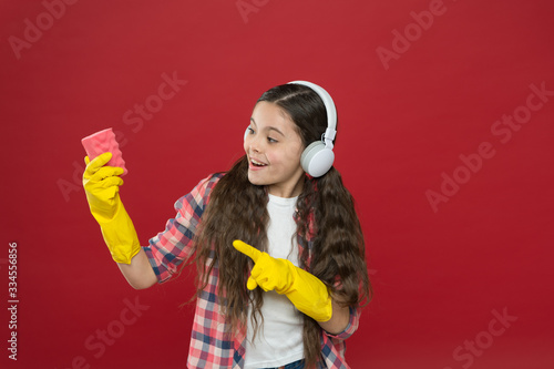 Everything is better with music. Make household more joyful. Harmless cleaner simple ingredients. Cleaning party. Girl wear headphones and protective gloves for cleaning. Listening music and cleaning