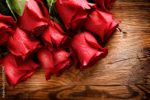 Red roses bouquet on old rustic table. Valentines day rose flowers background..