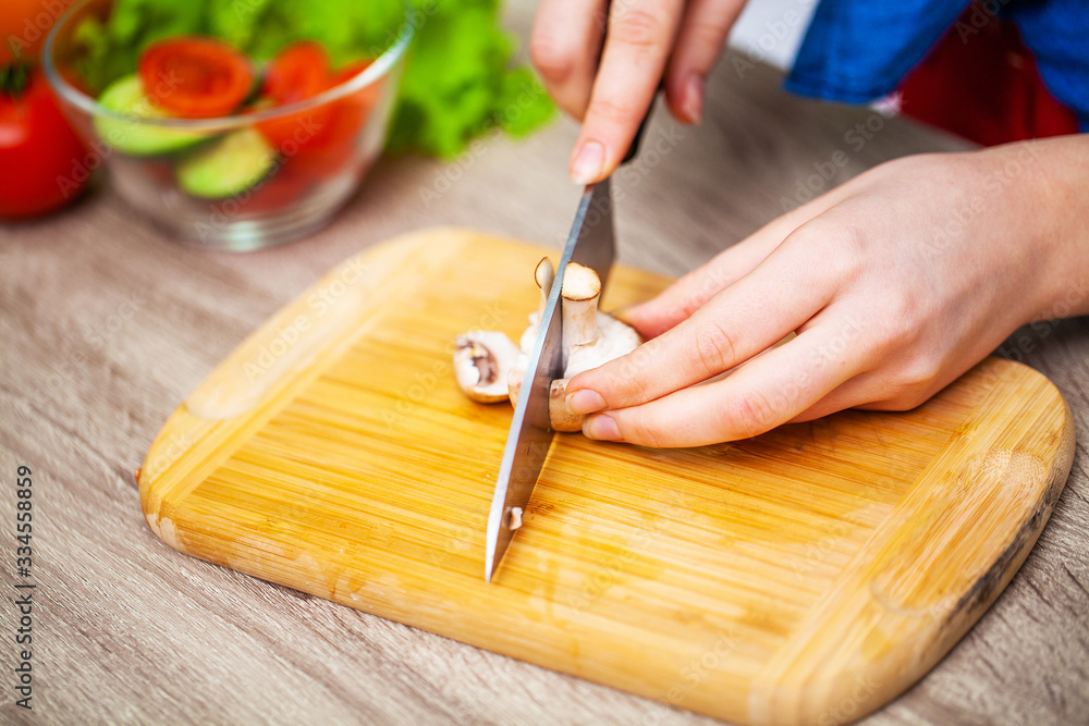Closeup of woman slices mushrooms for diet salad