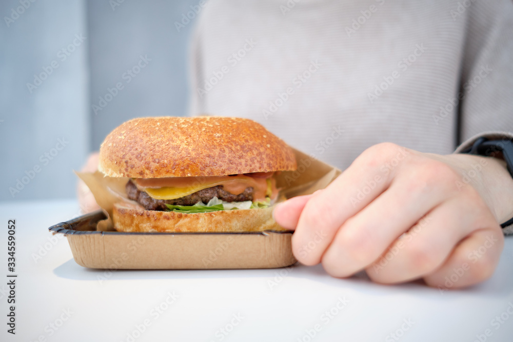Burger licks on the table in front of the girl. Burger licks on the table in front of the girl.