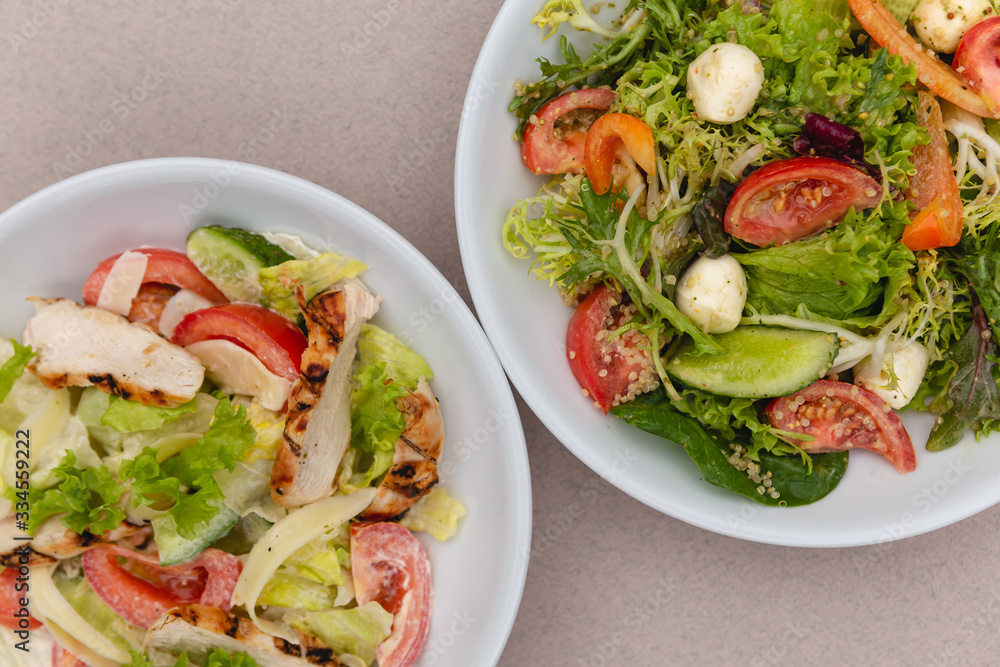 white deep plates with fresh salad ingredients mixed with sauce placed on an attractive background. A place for a menu, banner or advertisement white deep plates with fresh salad ingredients mixed with sauce placed on an attractive background. A place for a menu, banner or advertisement