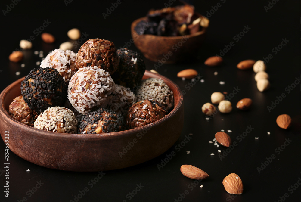 Energy balls of nuts, oatmeal and dried fruits on a brown plate on a black background, horizontal format Energy balls of nuts, oatmeal and dried fruits on a brown plate on a black background, horizontal format