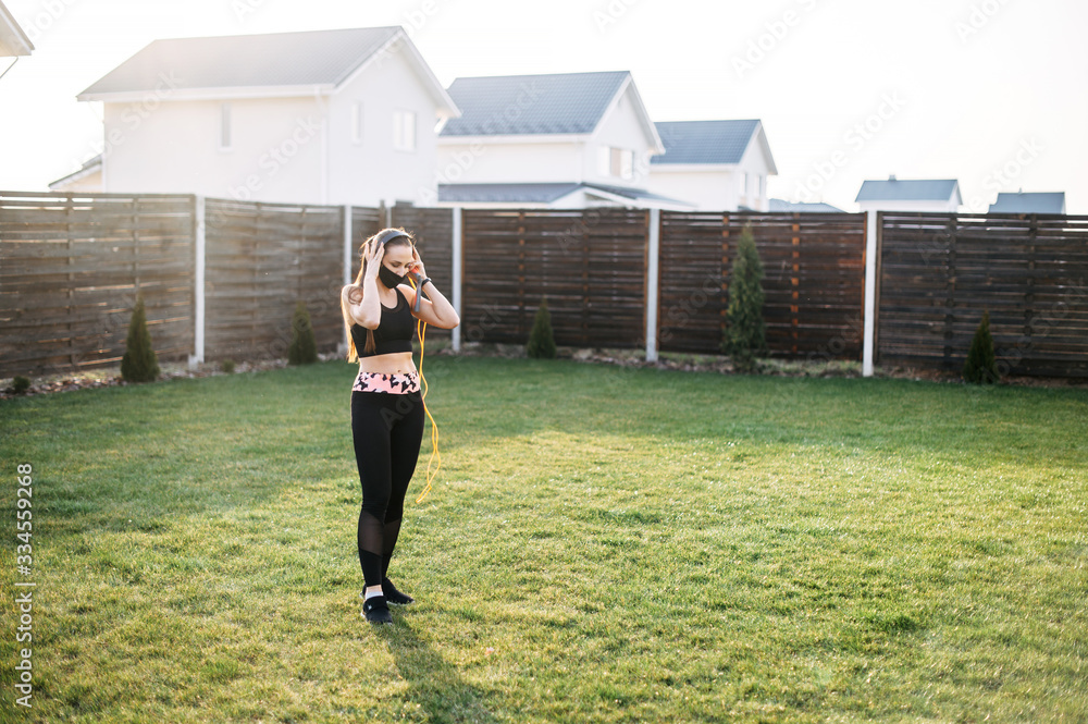 Woman in mask doing cardio workout in the backyard