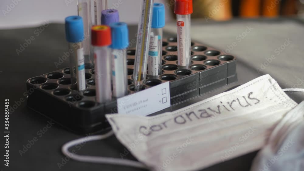 Coronavirus, nowhere to run. Medical test tubes are in the organizer. An inscription on a white sheet of paper. Medical disposable gauze bandages are on the table. A mercury glass thermometer is Coronavirus, nowhere to run. Medical test tubes are in the organizer. An inscription on a white sheet of paper. Medical disposable gauze bandages are on the table. A mercury glass thermometer is