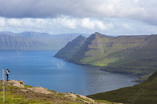 Hiker takes pictures of the fjords, Funningur, Eysturoy island, Faroe Islands, Denmark